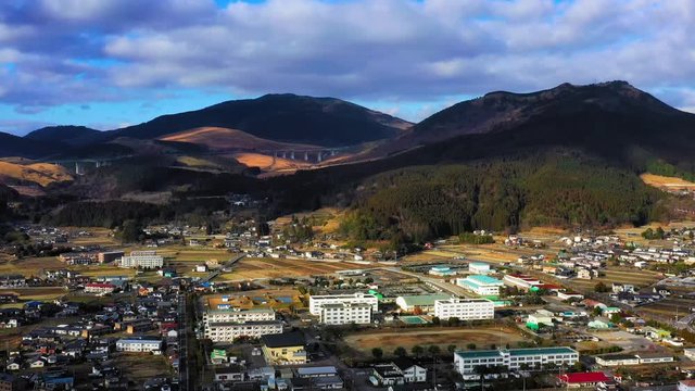 Colorful landscape at sunrise of Yufuin city in Japan, surrounded by green hills and mountains under grey clouds