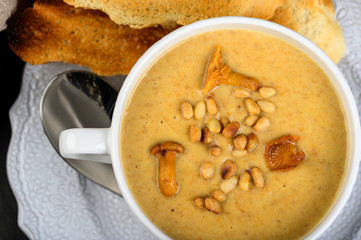 Mushroom, chanterelle cream soup with pine nuts and croutons on dark background
