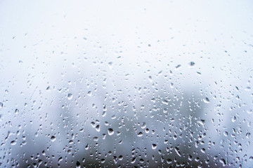 Window overlooking a rainy street. Gloomy evening weather with a view of the road. Drops on glass and bokeh from cars. Stock background for design