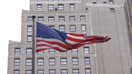 Flag of the United States waving in the wind in slow motion with an office building in the background in downtown Manhattan, New York City, USA - Powered by Adobe
