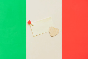 Note with a symbolic heart on the background of the national Italian flag. Concept of support and...
