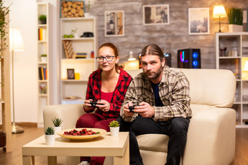 Gamers couple playing video games on the TV with wireless controllers in hands