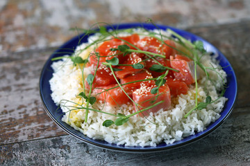 Selective focus. Plate with rice and salmon. Poke bowl with salmon and microgreens. Healthy food.