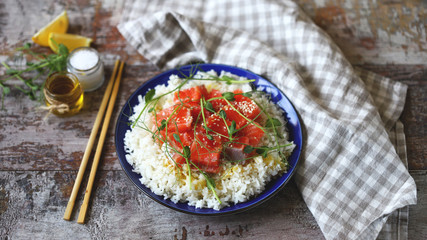 Selective focus. Plate with rice and salmon. Poke bowl with salmon and microgreens. Healthy food.