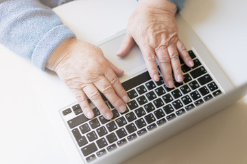 Fototapeta na wymiar Closeup senior old woman hand on laptop keyboard surfing and browsing internet at home with free and copy space. Technology, communication, information concept