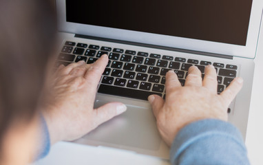 Fototapeta premium Closeup senior old woman hand on laptop keyboard surfing and browsing internet at home with free and copy space. Technology, communication, information concept