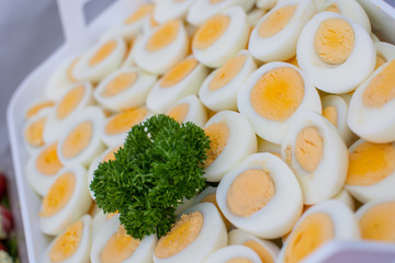 A whole bunch of sliced hard boiled eggs decorated with parsley on a buffet on a festive setting