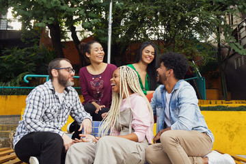 Brazilian group of young adult friends having fun laughing and enjoying a joke outside. Diversity...