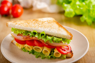 Ham sandwich on a plate on the table. Quick snack. Fast food.
