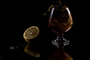The silhouette of a glass on a black background in which liquid is poured from above with splashes