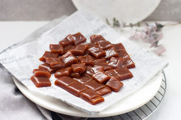 Salted caramel candies cut into square pieces, top view over grey baking paper