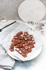 Salted caramel candies cut into square pieces, top view over grey baking paper