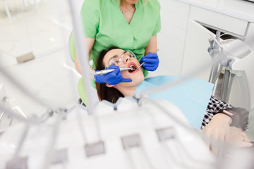 Young beautiful woman treats teeth at the dentist cabinet. Dental treatment process
