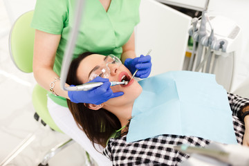 Young beautiful woman treats teeth at the dentist cabinet. Dental treatment process