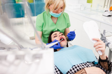 Young beautiful woman treats teeth at the dentist cabinet. Dental treatment process