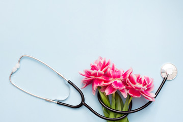 A Stethoscope on blue background with a spring flowers.