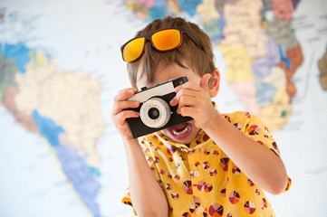 funny little journalist kid in yellow summer shirt and sunglasses taking picture on important moment using vintage film camera