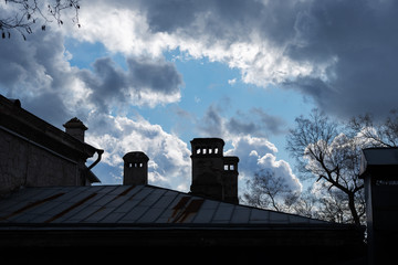 Roof of an old house with chimneys with a cloudy sky background