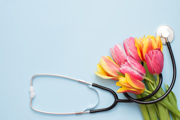 Stethoscope and colorful tulips on a blue background with a copy space