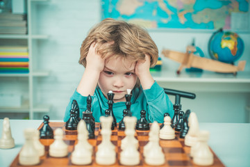 Clever concentrated and thinking child while playing chess. Thinking child. Chess, success and winning. Intelligent, smart ass kids. Games good for brain intelligence concept.