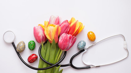 Bunch of colorful tulips, easter eggs and stethoscope on light background. Happy nurse day. Easter....