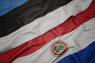 waving colorful flag of paraguay and national flag of estonia.