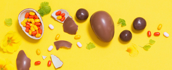 Easter yellow background with chocolatte eggs,    candy and spri