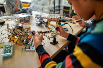 There is no impossible. Cropped shot of young engineer using soldering iron to join chips and wires. Robotics and software engineering for elementary students. Inventions and creativity for kids