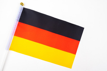 Flag Of Germany. Miniature German flag on a white table. Flag with black-red-yellow horizontal stripes. State symbol of the Federal Republic of Germany. Immigration. Work in another country.