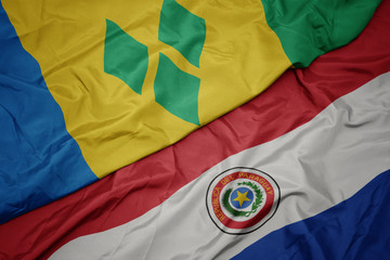 waving colorful flag of paraguay and national flag of saint vincent and the grenadines.