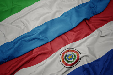 waving colorful flag of paraguay and national flag of sierra leone.
