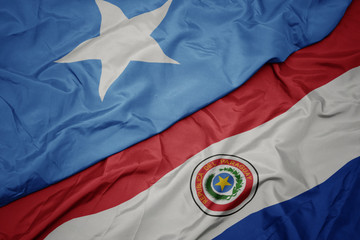 waving colorful flag of paraguay and national flag of somalia.