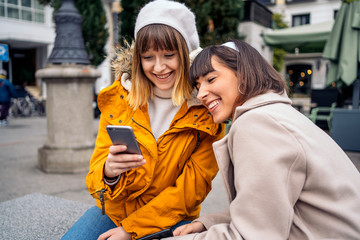 Two caucasian girls using a smartphone.