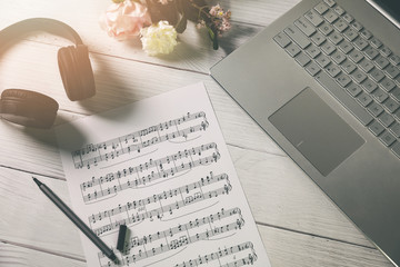 compose music and education - paper sheet with musical notes, laptop and headphones on the artist desk
