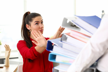 Young happy woman sitting in office and refusing to work with heap of documents