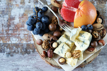 Selective focus. Healthy snack on a wooden tray. Cheese, nuts and fruits. Keto diet. Keto snack.
