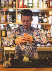Bartender preparando un cocktail durante su turno de trabajo, camisa colorida