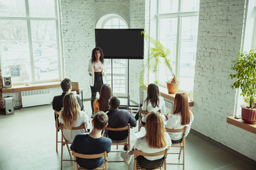 Female african-american speaker giving presentation in hall at workshop. Audience or hall. Rear...