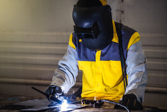 worker welding craftsman wearing safety helmet arc or welding for repairing a part of metal work in workshop, welding and construction concept