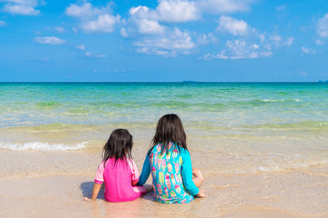 Fototapeta na wymiar Asian beautiful girl and her sister sitting at a beautiful beach in a summer time