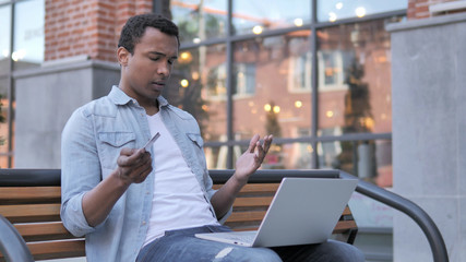 Online Shopping Failure for African Man Sitting on Bench