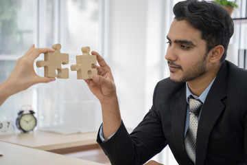 An asian business people sitting at office desk, putting puzzle pieces together, finding solution.