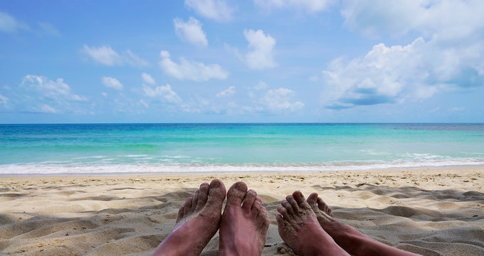Two feets women and men on the beach with beautiful blue azul sea.