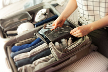 Open grey suitcase with different clothes packed for journey at home. Nordic style minimalism....