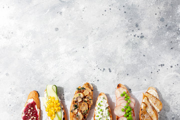 Assorted bruschetta or tapas set with different savory and sweet topping on gray concrete...