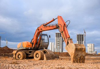 Bucked wheel excavator digs ground at a construction site for installing concrete storm pipes....