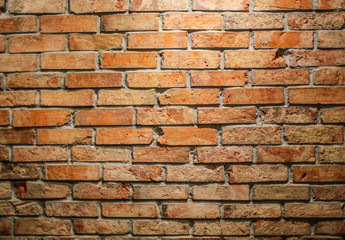 Brick wallpaper in a cafe is lit by a lamp from above. The wall of the old red brick in a bar