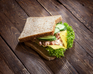 tuna sandwich with fresh green salad and cucumbers on rustic wooden table surface