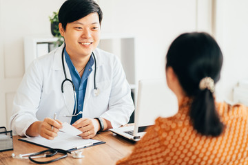 Asian doctor and female patient talking in clinic