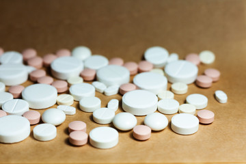 Heap of white pills, tablets, capsules on yellow orange background. Drug prescription for treatment medication health care concept wth copy space.
